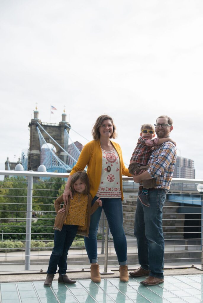 A family of four posing with a bridge in the background.