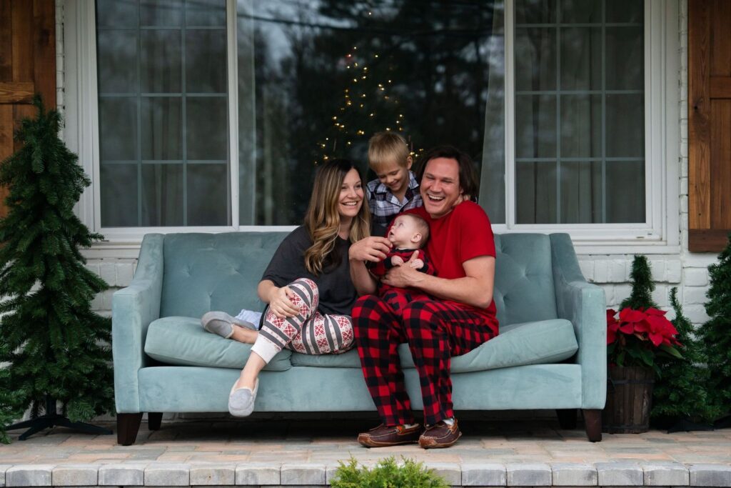 A family of four enjoying time together on a porch sofa during the holiday season.