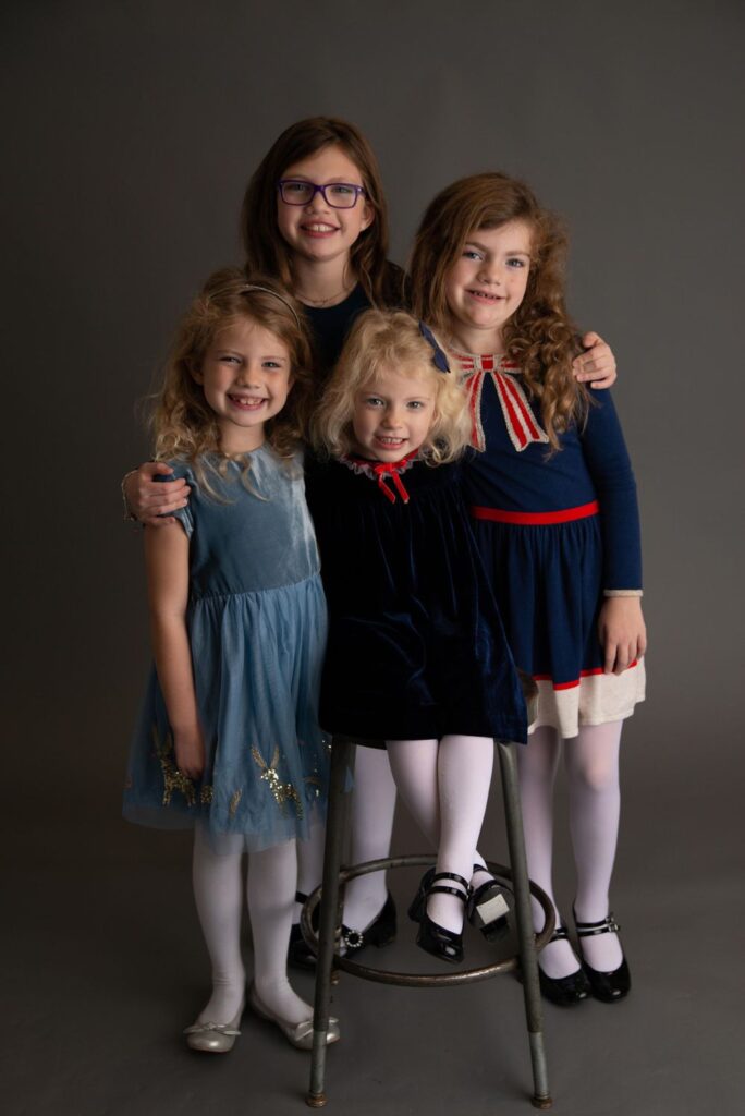 Four smiling children posing together for a portrait.
