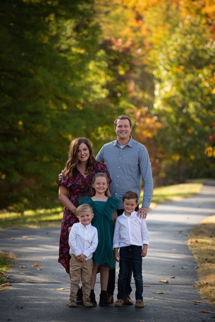 A family is posing for a family photo in the fall.