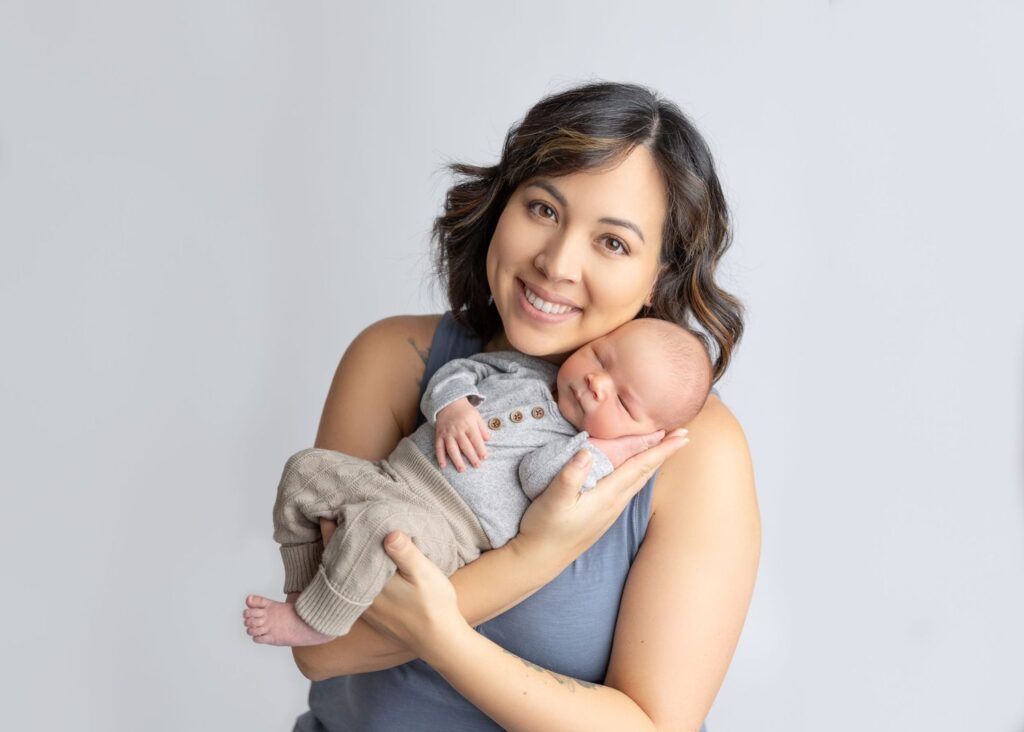 Woman smiling and holding a sleeping newborn baby.