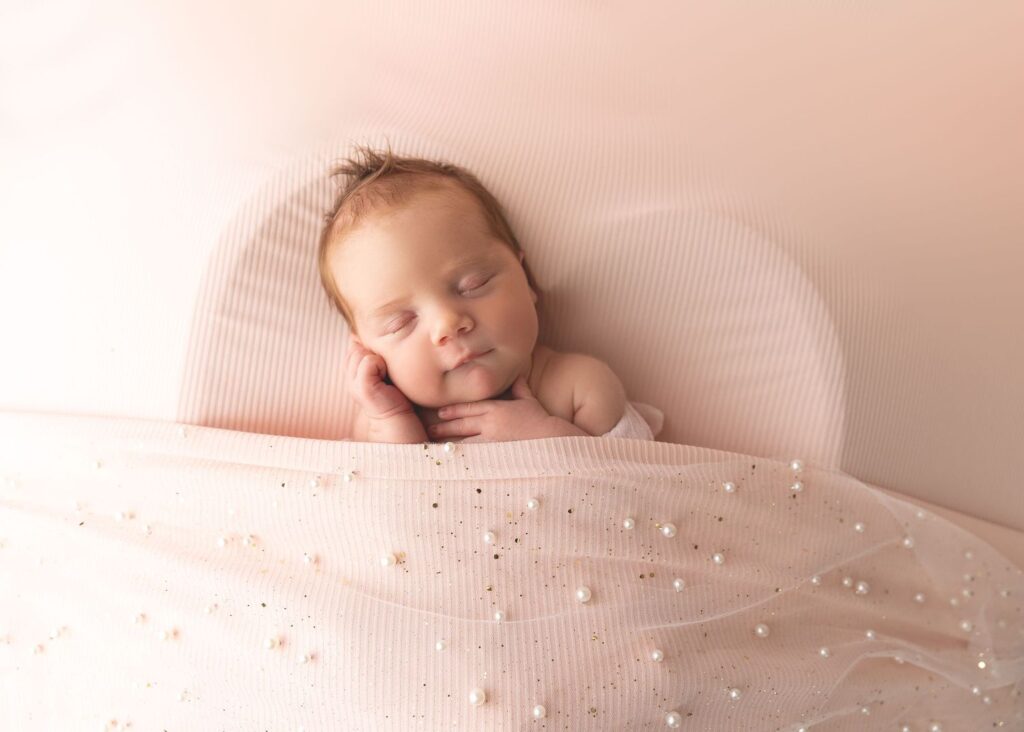 Newborn baby sleeping peacefully on a soft fabric surface.