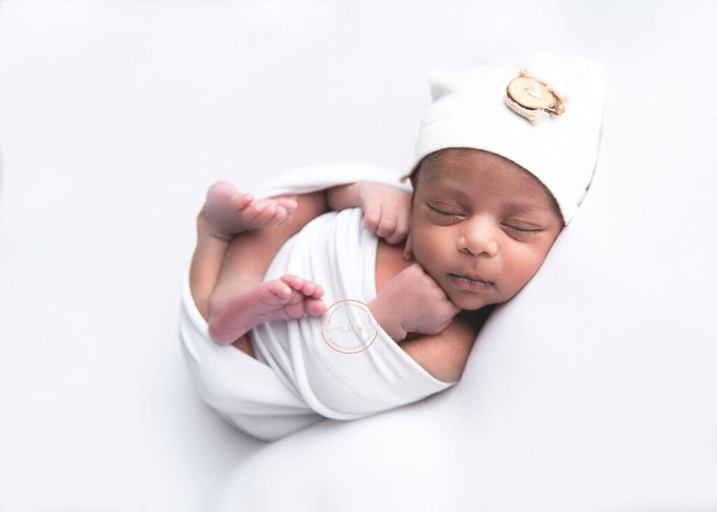 Newborn baby swaddled in white, sleeping peacefully.