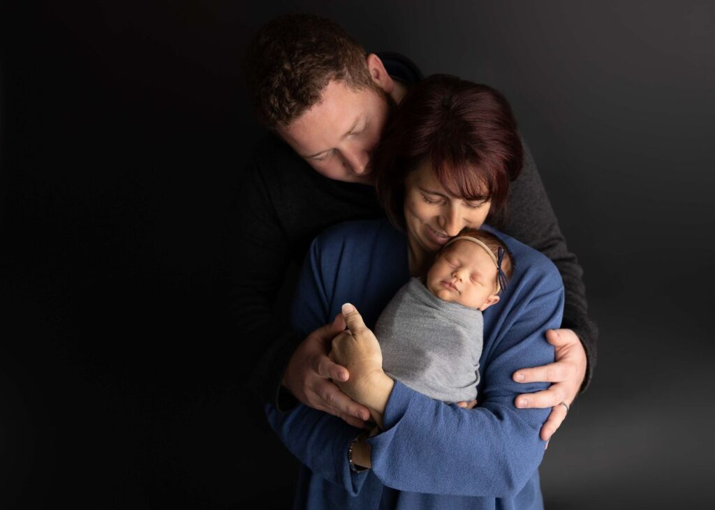 A family with a newborn baby sharing a tender embrace.
