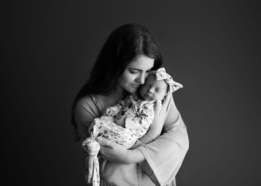 A woman tenderly cradling a sleeping infant in a serene, black and white portrait.